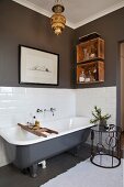 Free-standing vintage bathtub and side table with wrought iron frame in bathroom with grey walls and white tiling