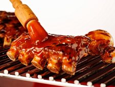 Spare ribs being brushed with barbecue sauce