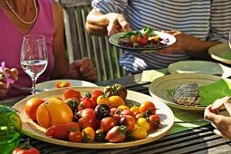 Menschen essen Tomaten auf einem sommerlichen Gartentisch