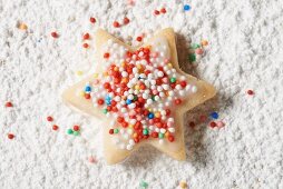 Sternplätzchen mit bunten Zuckerperlen auf Puderzucker