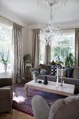 Wooden coffee table and grey sofa set in living room with Venetian-style glass chandelier hanging from stucco ceiling rose