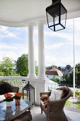 Wicker armchairs and table on roofed, old-fashioned terrace with columns