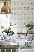 Table set with white crockery and vase of flowers in dining room with botanical wallpaper
