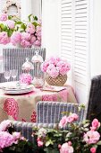 Table on terrace decorated with pink mophead hydrangeas