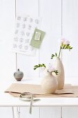 Pale ceramic vases of freesias on table