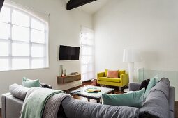 Lounge area with corner sofa, yellow armchair and designer standard lamp