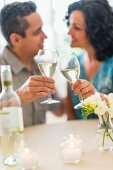 A couple celebrating in a restaurant and raising a toast with white wine