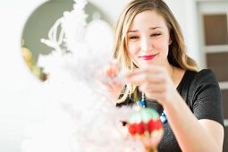 Junge Frau dekoriert den Weihnachtsbaum