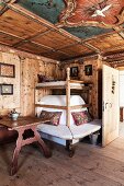 Old stove bench and tiled stove in wood-panelled dining room of chalet with antique, farmhouse furnishings