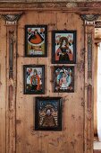 Gerahmte Folklorebilder zwischen kunstvoll verzierten Lisenen auf holzvertäfelter Wand