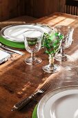 Rustikale Stielgläser und grüne Filzsets auf gedecktem Bauerntisch