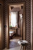 Blick vom Flur in Gästezimmer mit braun-weißer Textiltapete und geometrischem Muster