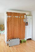 Old wardrobe and white metal lockers used as partition; numbers painted on back of wooden wardrobe with vintage suitcase and green footstool on floor