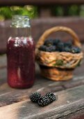 A blackberry smoothie and fresh blackberries on a wooden surface