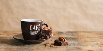 A chocolate and pecan nut brownie next to an espresso cup