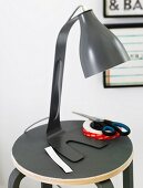 A black retro table lamp on a matching stool with a pair of scissors and sticky tape next to it