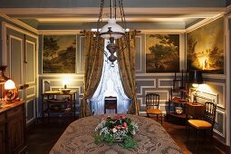 Elegantly furnished dining room with blue and white wood panelling and antique paintings