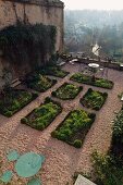 Terrace garden with rectangular beds, gravel paths and view of historical town in morning mist