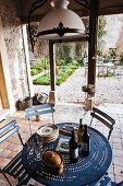 Antique, French glass lamp above round metal table with perforated pattern and view into historical gravel garden