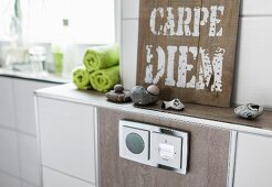 Detail of a built-in radio set in a light brown wall tile with stones and a 'Carpe Diem' sign on the shelf above