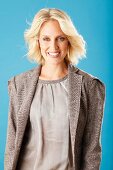 A young blonde woman wearing a taupe silk blouse and a matching blazer