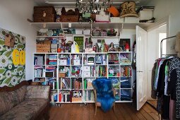 Storage against end wall on mobile shelving and fitted shelf below ceiling; antique sofa against floral panel to one side