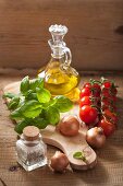 Stillleben mit Zwiebeln, Tomaten, Gewürzen, Basilikum und Olivenöl
