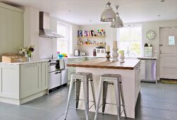 Retro, metal bar stools at free-standing island counter in open-plan, country-house kitchen