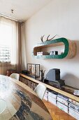 View across dining set of hand-crafted, curved shelf above sideboard with collection of magazines