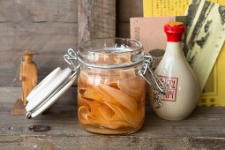 Sweet-and-sour pickled ginger in a flip-top jar on a wooden shelf