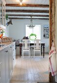 Blue from kitchen to dining area below chandelier hanging from wood-beamed ceiling