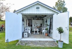 View into converted garage with cosy, vintage furnishings and storage for gardening implements