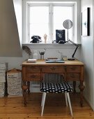 Vintage desk and vintage stool below window with rotary dial telephone on windowsill