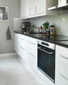 White, designer kitchen with splashback and white-painted wooden floor