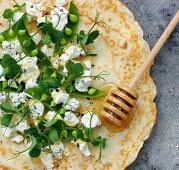 A pancake topped with goat's cheese, peas and honey