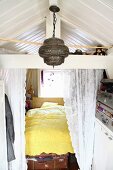 Cubby bed behind lace curtain, Oriental pendant lamp and storage in vintage suitcases