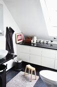Modern, white bathroom with fitted cabinets under sloping ceiling with bird wall stickers and black accessories