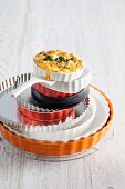 Stack of baking tins with a mini quiche on top