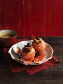 Two baked apples with fruit and nuts on a ceramic plate