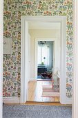 Floral wallpaper on wall of foyer with open doorway and view of toy car in room beyond