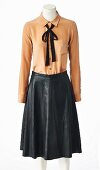A long-sleeved beige silk blouse and black leather skirt