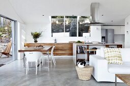 Designer kitchen with dining area in open-plan interior; white couch in foreground