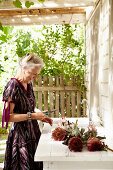 Woman with proteas on terrace with sink adjoining house