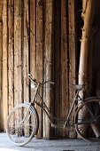 Vintage bicycle in front of stock of wooden beams in barn of rough-wood carpenter's workshop