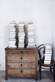 Stacked books on old chest of drawers next to Thonet chair