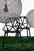Spherical pendant lamps (Random Light) made from fibreglass mesh and designer chairs with hexagonal struts on lawn