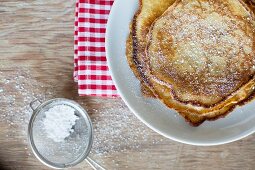 A stack of pancakes dusted with icing sugar (seen from above)