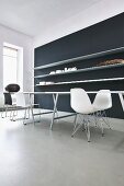 Purist tables, classic chairs and black wall with long, white, floating shelves