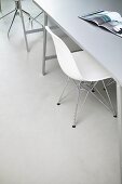 Weisser Schalenstuhl von Eames an Tisch mit aufgeschlagener Zeitung