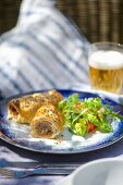 Sausage rolls with salad and a beer